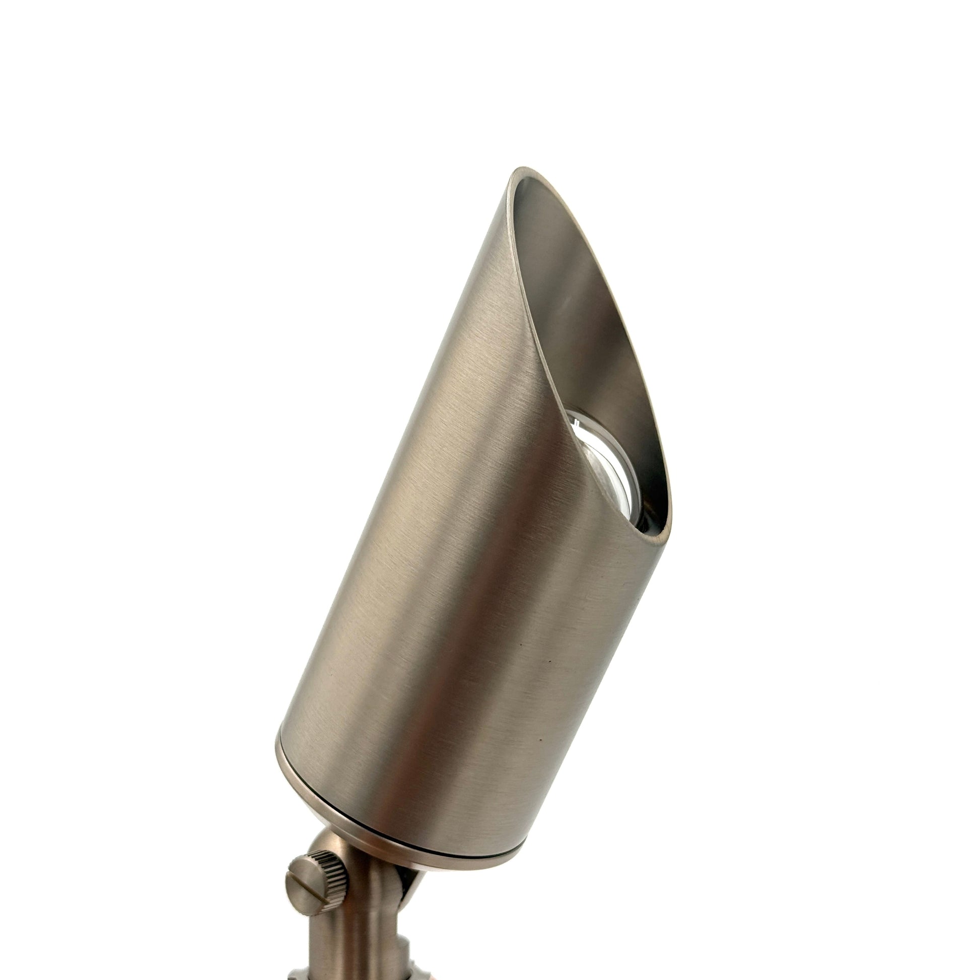 A brushed metal outdoor landscape light with a tapered cone-shaped head, held by a hand against a solid white background.